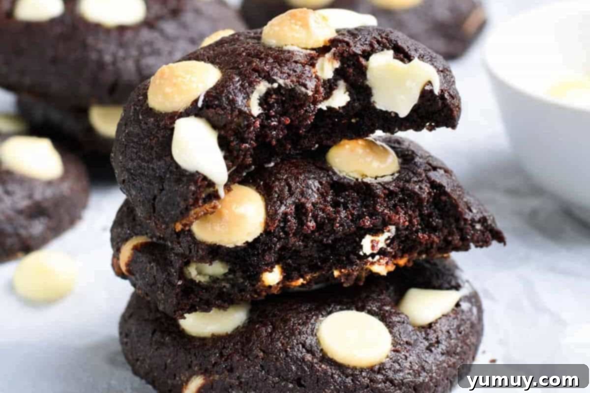 Closeup of a stack of perfectly baked chocolate white chocolate chip cookies, with one bitten to show the soft interior.