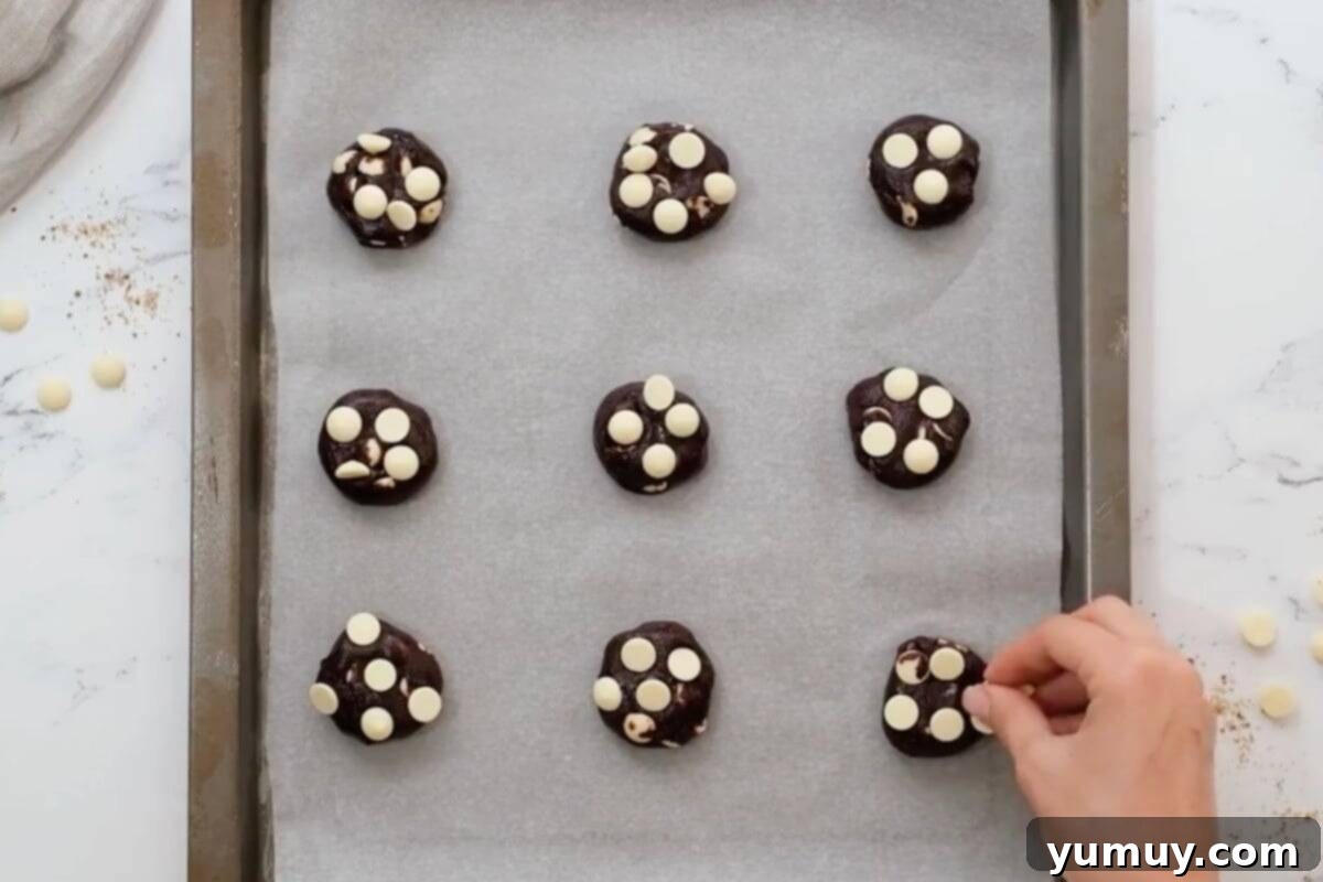 Topping chocolate white chocolate chip cookie dough balls with a sprinkle of extra white chocolate chips for presentation.