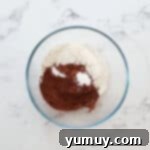 Flour, baking powder, and cocoa powder combined in a glass bowl.