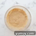 Egg and vanilla extract added to the creamed butter and sugars in a glass bowl.