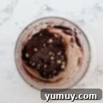 Thick chocolate cookie dough with white chocolate chips folded in, in a glass bowl.