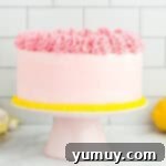 Vibrant Strawberry Lemon Cake 14 side view of pink frosted cake on a cake stand.