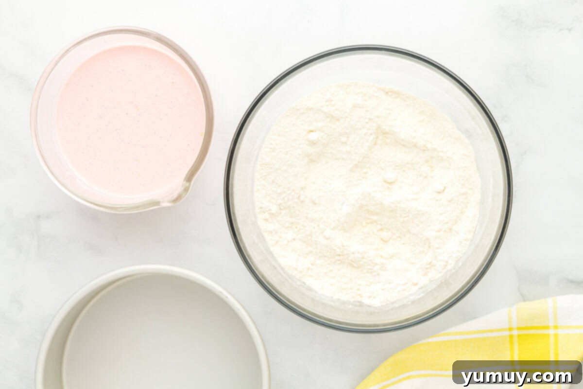 Vibrant Strawberry Lemon Cake 16 dry cake mix in a glass bowl next to a bowl of pink liquid.