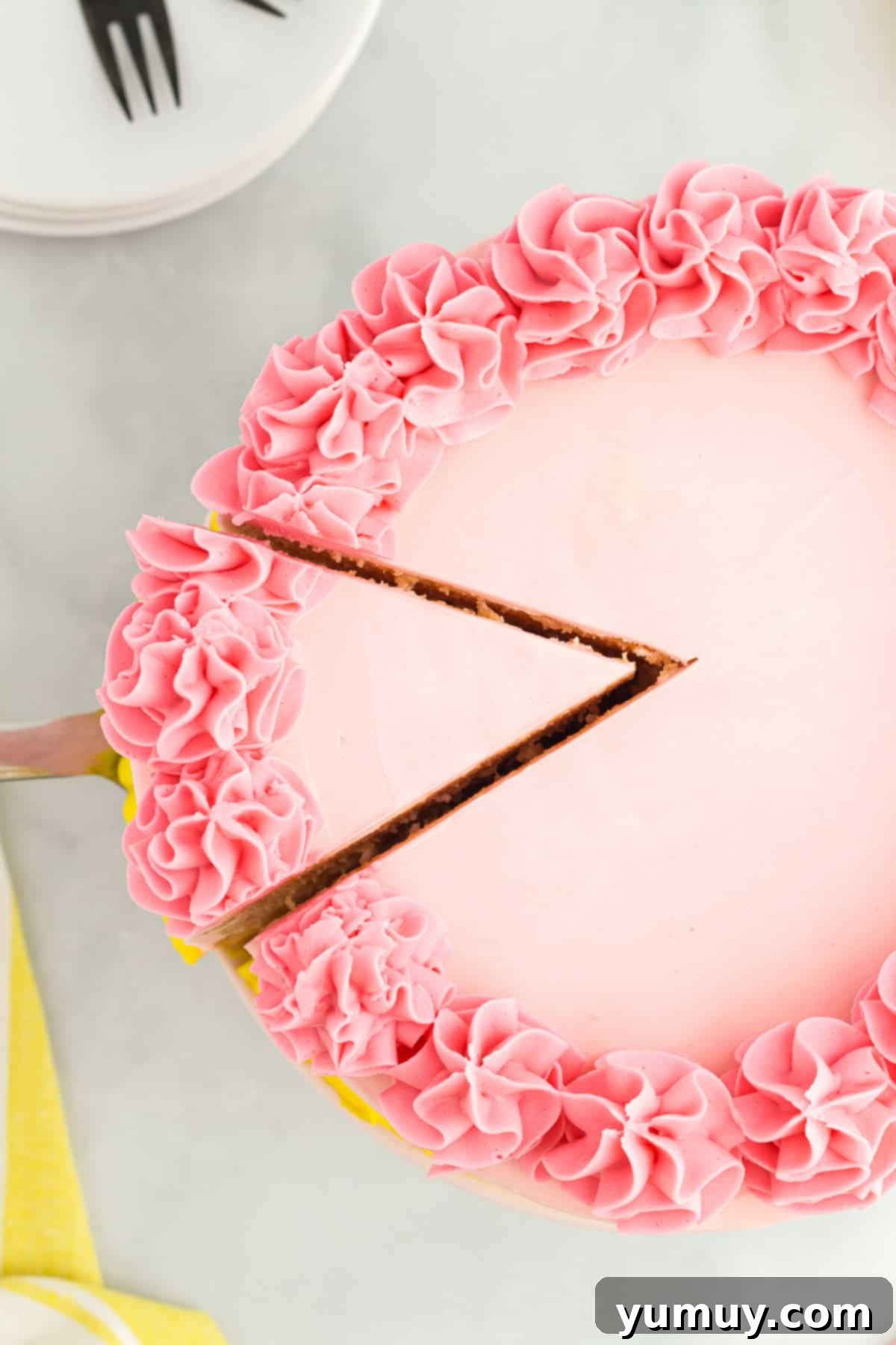 Vibrant Strawberry Lemon Cake 3 overhead view of a cake server removing a slice of pink lemonade cake from a whole cake.