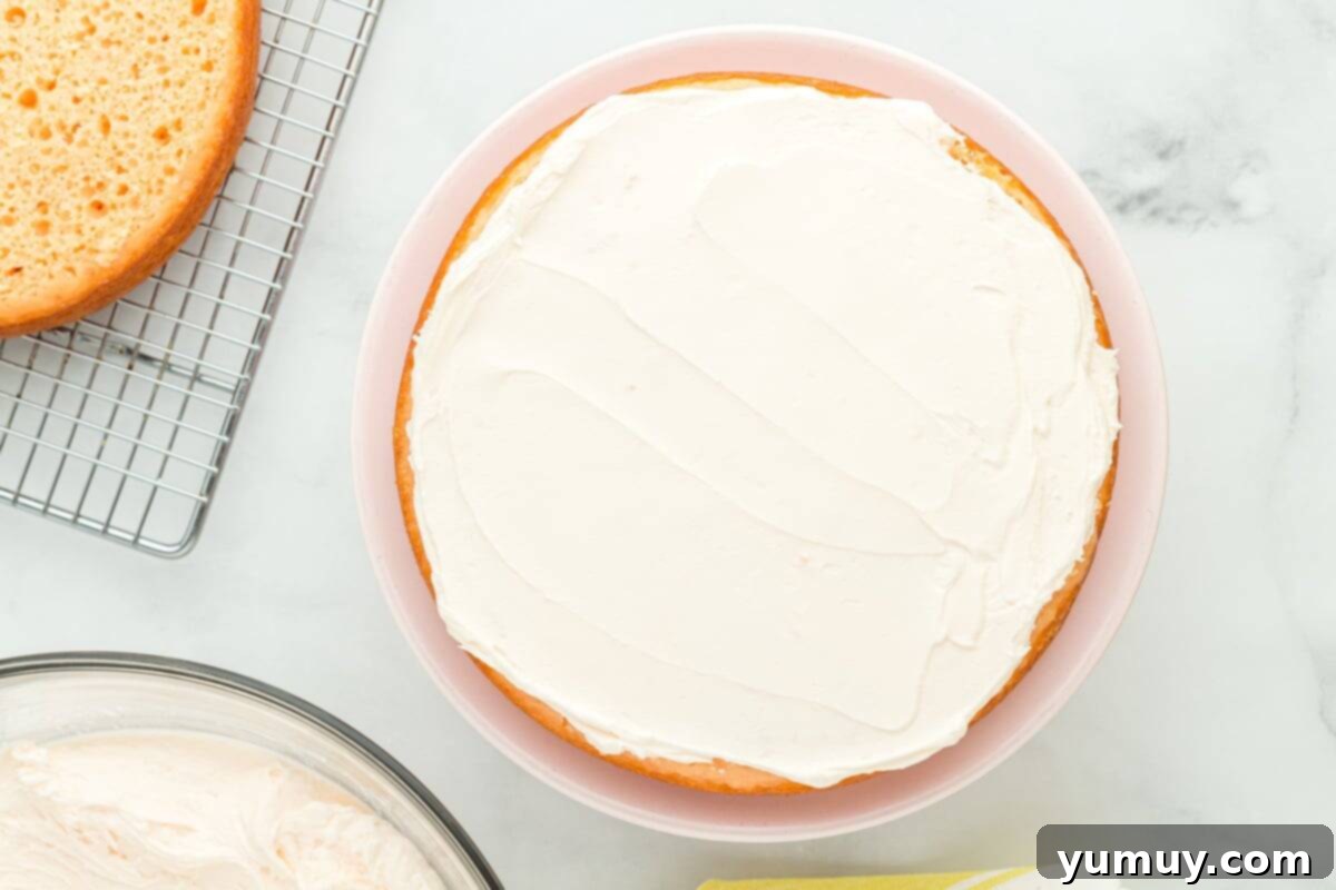 Vibrant Strawberry Lemon Cake 22 a single layer of cake with white frosting on top on a cake stand.