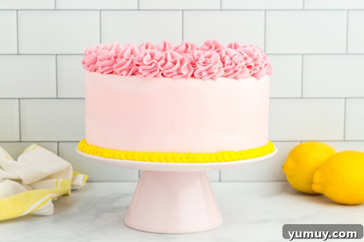 Vibrant Strawberry Lemon Cake 24 side view of pink frosted lemonade cake on a cake stand.