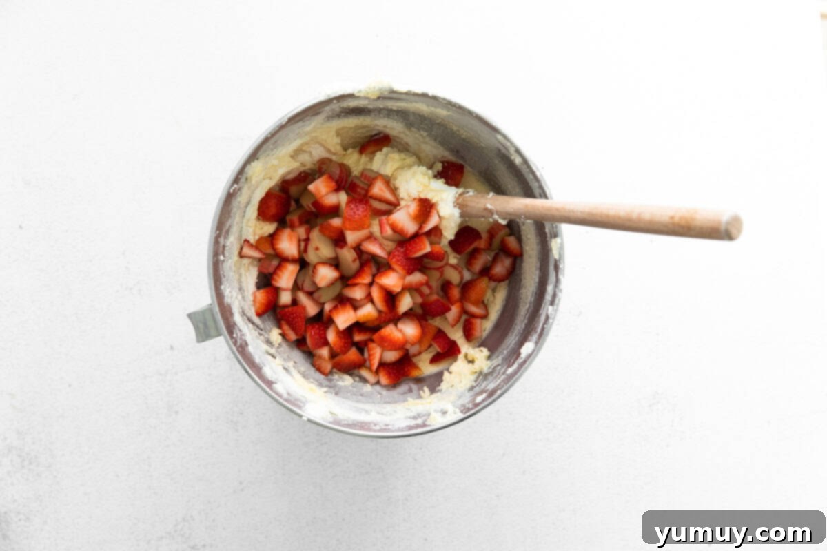 folding chopped strawberries and rhubarb into cake batter with a rubber spatula.