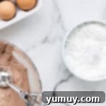 Cool Whip Cloud Cookies 7 a coated chocolate cookie dough ball in a bowl of powdered sugar.
