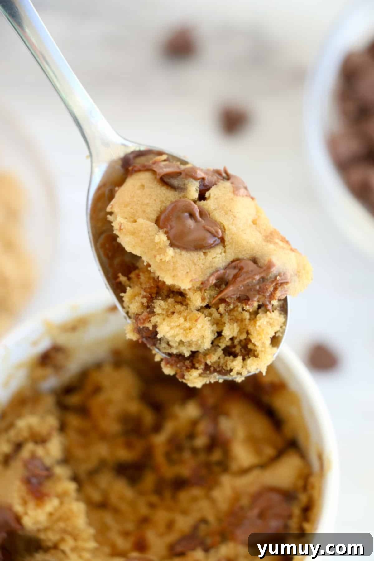 Decadent Peanut Butter Mug Delight 3 A spoon lifting a scoop of peanut butter mug cake from a white mug, showing its soft interior.