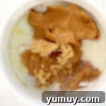 Decadent Peanut Butter Mug Delight 5 Wet ingredients added to dry for peanut butter chocolate chip mug cake in a white mug.