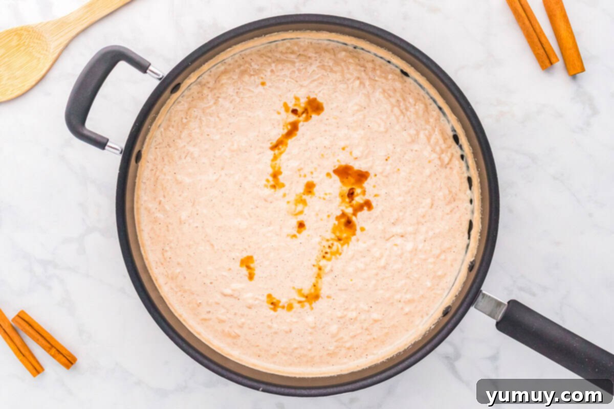 a swirl of vanilla extract on cooked rice pudding in a saucepan.
