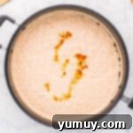 a swirl of vanilla extract on cooked rice pudding in a saucepan.