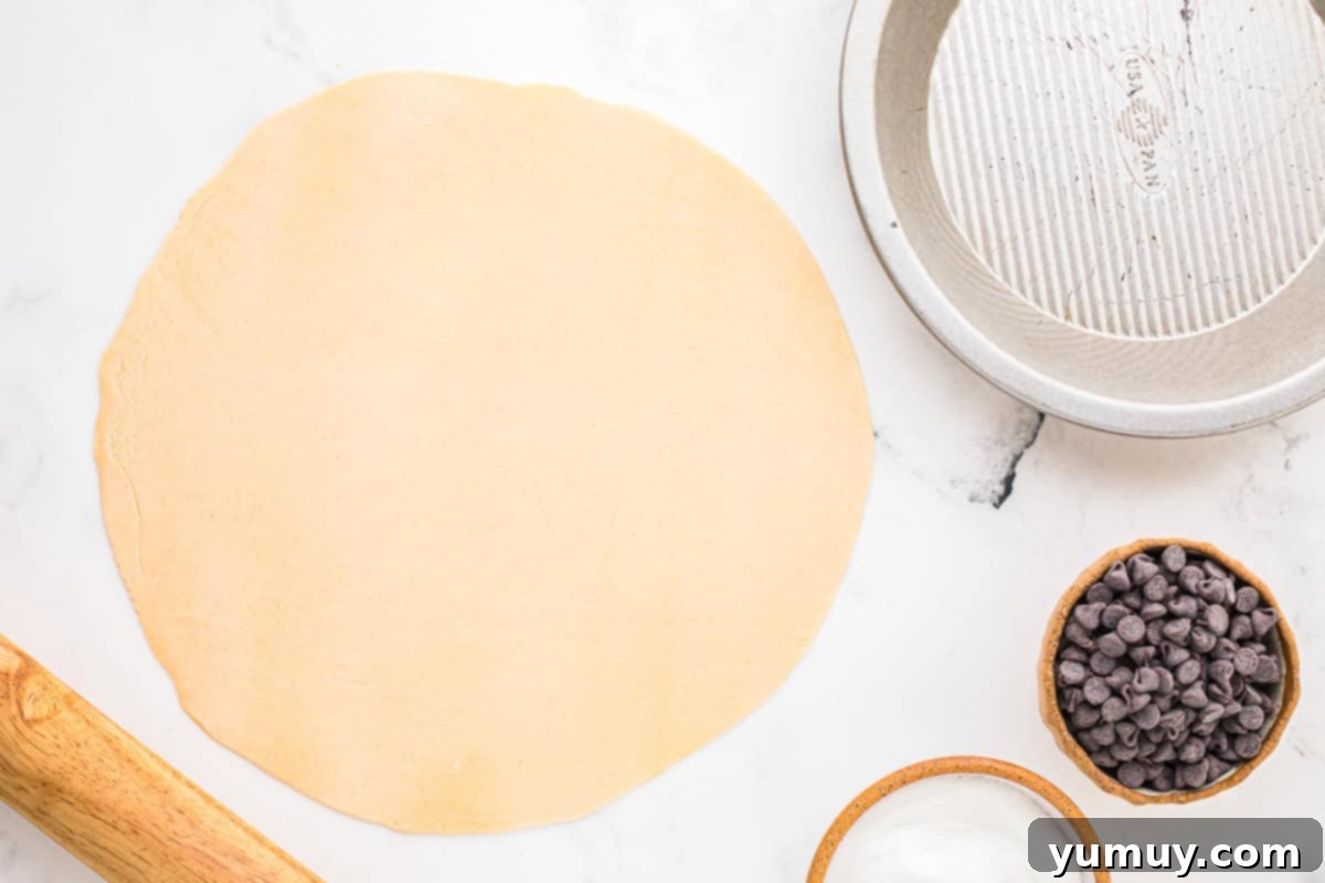 German Chocolate Coconut Pecan Delight Pie 15 A sheet of rolled-out pie crust, flattened and prepared on a clean work surface, ready to be placed into the pie pan.