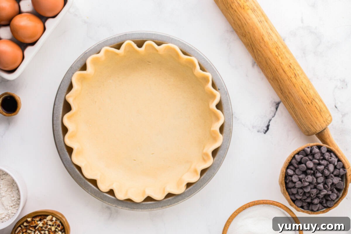 German Chocolate Coconut Pecan Delight Pie 16 A pie crust meticulously crimped around the edges within a pie pan, showcasing neat folds and a ready-to-bake appearance.