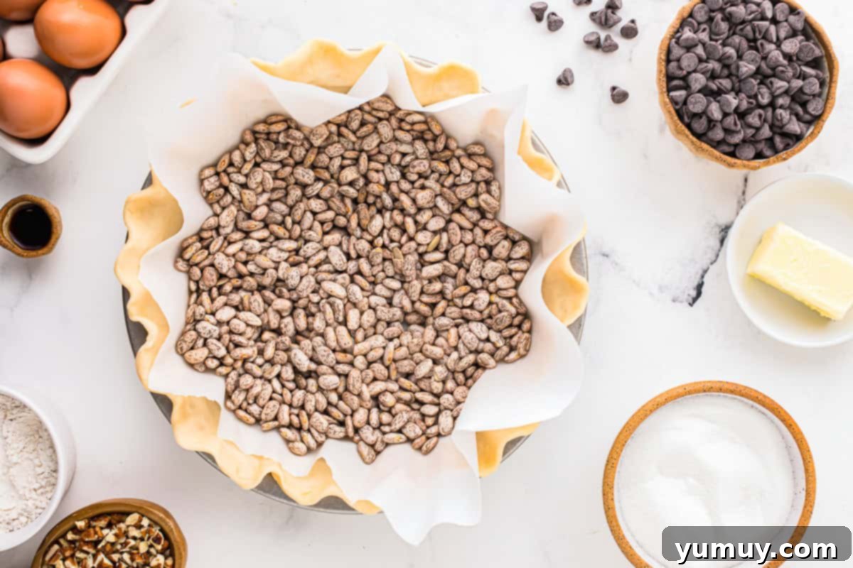 German Chocolate Coconut Pecan Delight Pie 17 A crimped pie crust in a pie pan, covered with parchment paper and filled with pie weights, ready for blind baking.