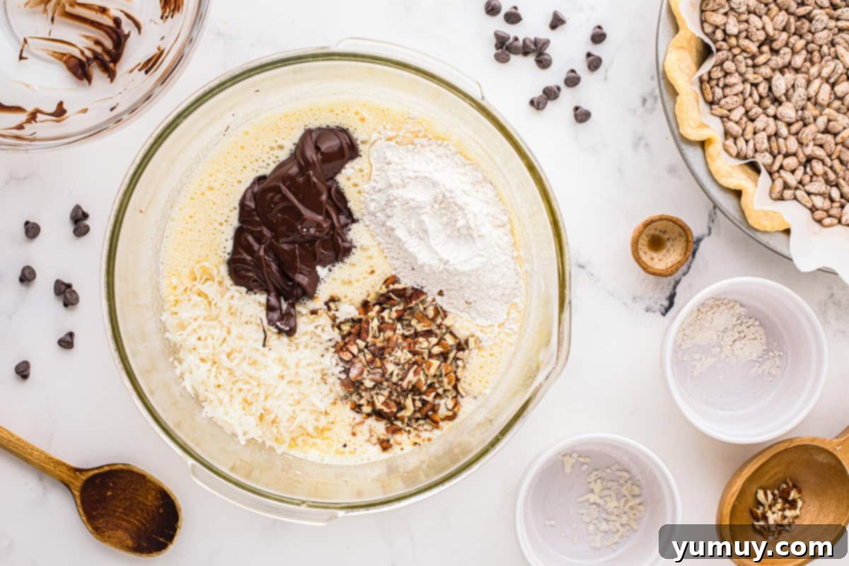 German Chocolate Coconut Pecan Delight Pie 20 A close-up of a glass bowl where melted chocolate, coconut flakes, pecans, and flour are being folded into a frothy egg mixture, creating a rich filling.