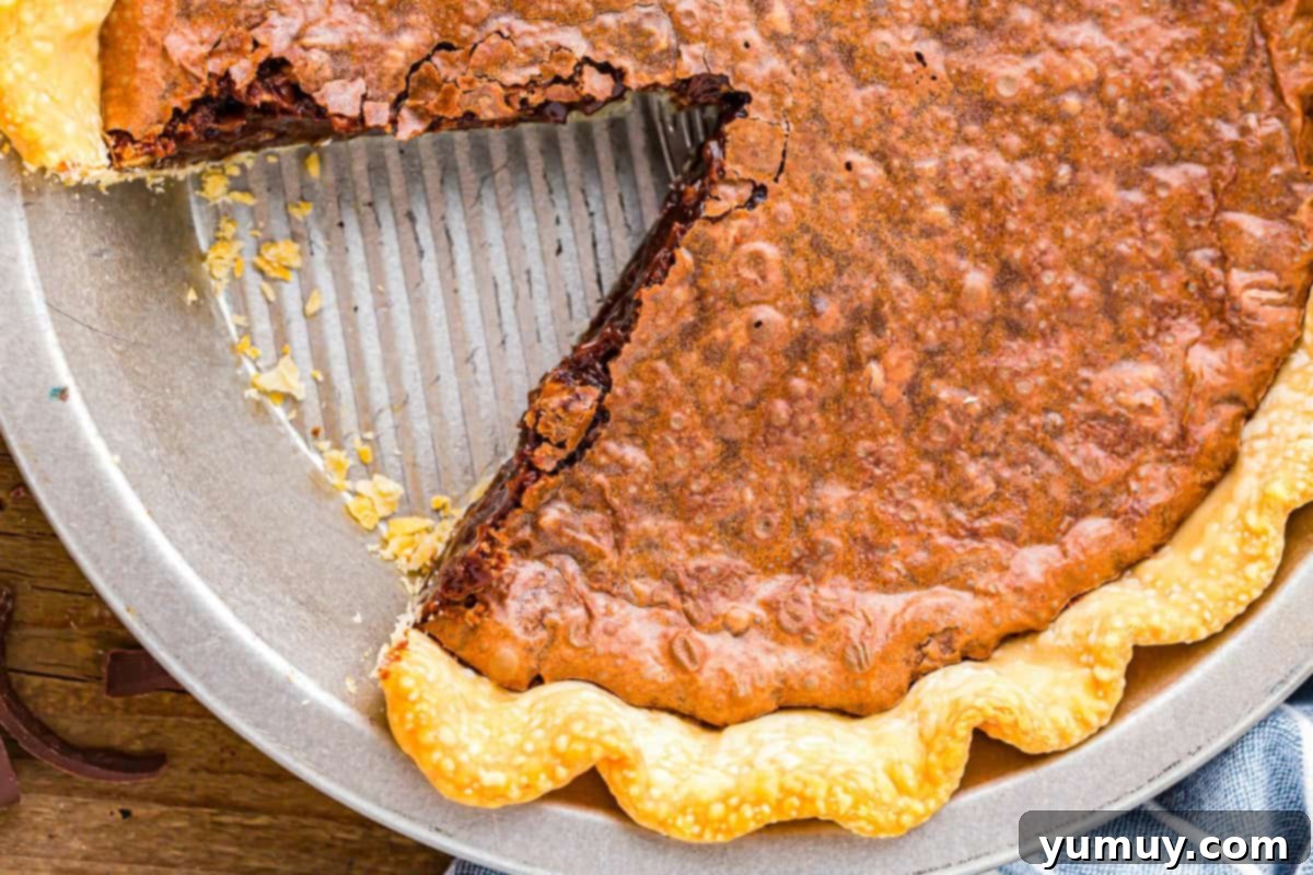 German Chocolate Coconut Pecan Delight Pie 3 An overhead view of a freshly baked German chocolate pie in a pie pan, with one inviting slice already removed, revealing its rich, layered interior.