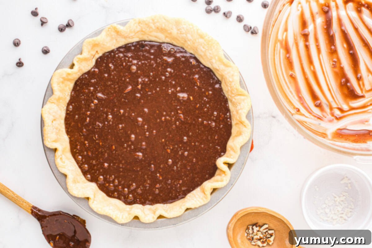 German Chocolate Coconut Pecan Delight Pie 21 The dark, rich German chocolate pie filling, studded with coconut and pecans, has been smoothly poured into a par-baked pie crust within a pie pan, ready for the oven.