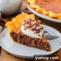 German Chocolate Coconut Pecan Delight Pie 4 A slice of German chocolate pie topped with whipped cream and pecans on a plate with a fork.