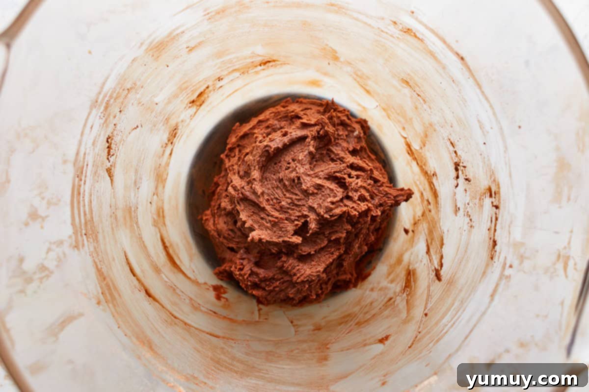 Sticky chocolate cookie dough in a glass bowl after all ingredients and mix-ins have been combined, awaiting chilling.