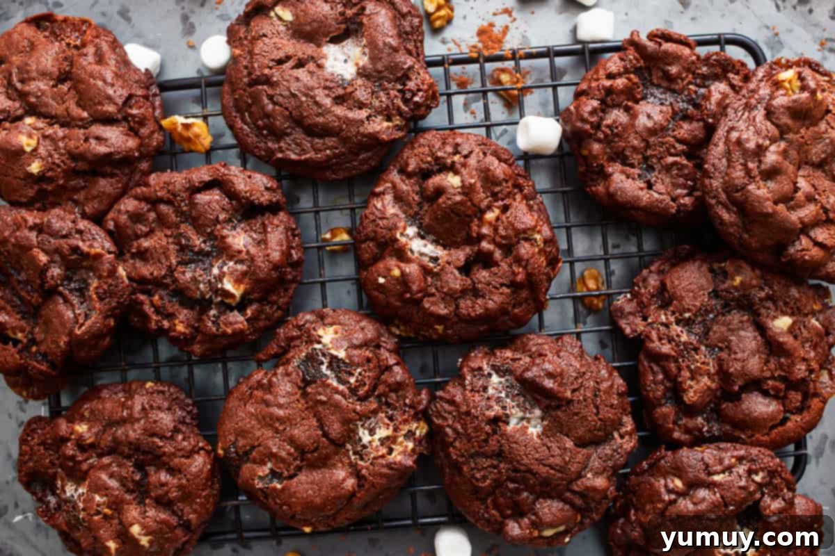 Overhead view of freshly baked rocky road cookies cooling on a wire rack, steam gently rising.