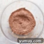 Sifted dry ingredients (flour, cocoa, baking soda) in a glass bowl.