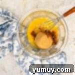 Vinegar Pie A Slice of Humble Pie: The Unexpected Delight 6 Eggs, brown sugar, granulated sugar, melted butter, apple cider vinegar, vanilla, cinnamon, salt, and nutmeg in a glass bowl with a whisk.