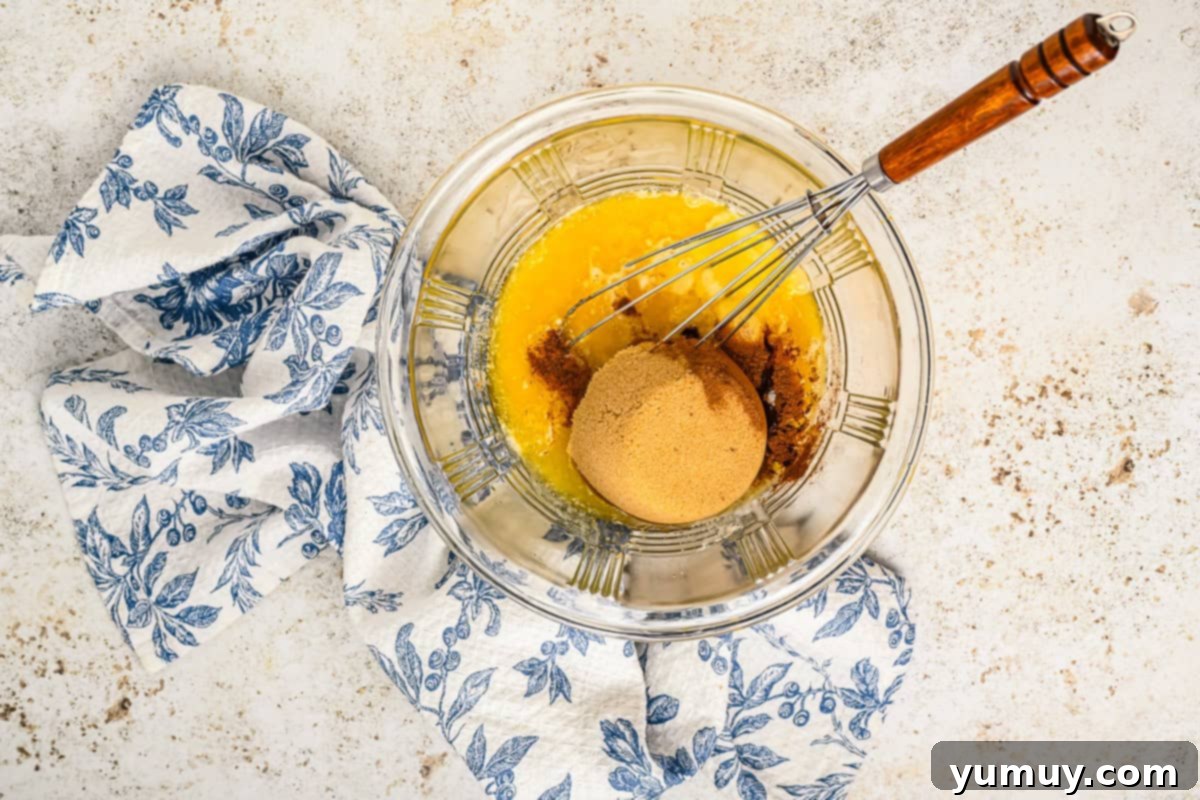 Vinegar Pie A Slice of Humble Pie: The Unexpected Delight 10 A glass bowl containing the mixed vinegar pie filling, showcasing the eggs, brown sugar, granulated sugar, melted butter, apple cider vinegar, vanilla, cinnamon, salt, and nutmeg, with a whisk resting in the bowl.