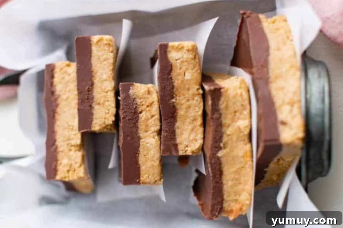 Peanut Butter Dream Bars 3 a stack of no bake peanut butter bars separated by parchment in a baking pan.