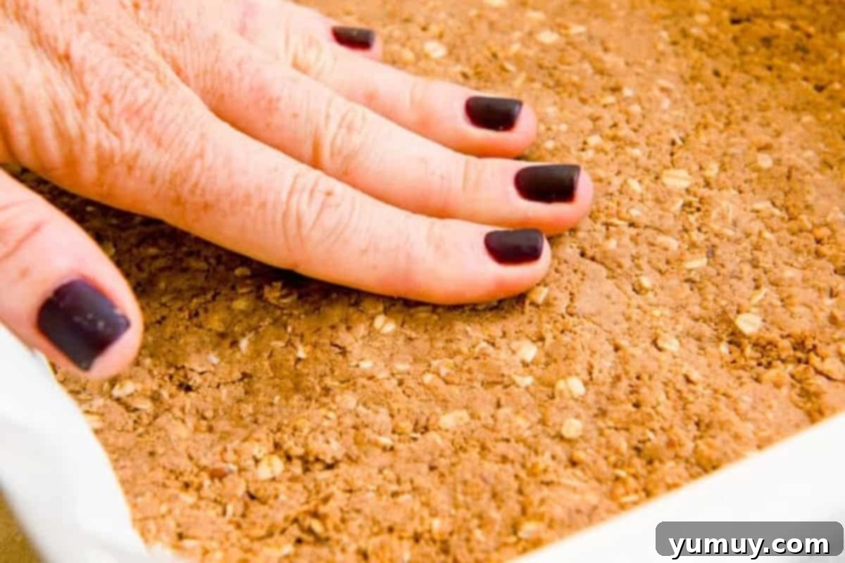 Crafting Your Perfect Protein Bars 10 pressing homemade protein bar mixture into a lined baking pan.