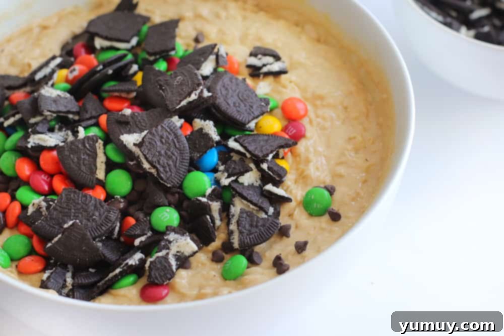 Crumbled Oreos and M&M's artfully piled atop the cookie dough, ready to be folded in.