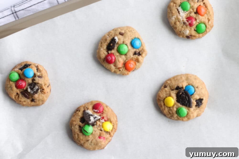 Freshly baked Oreo monster cookies cooling on a parchment-lined baking tray.