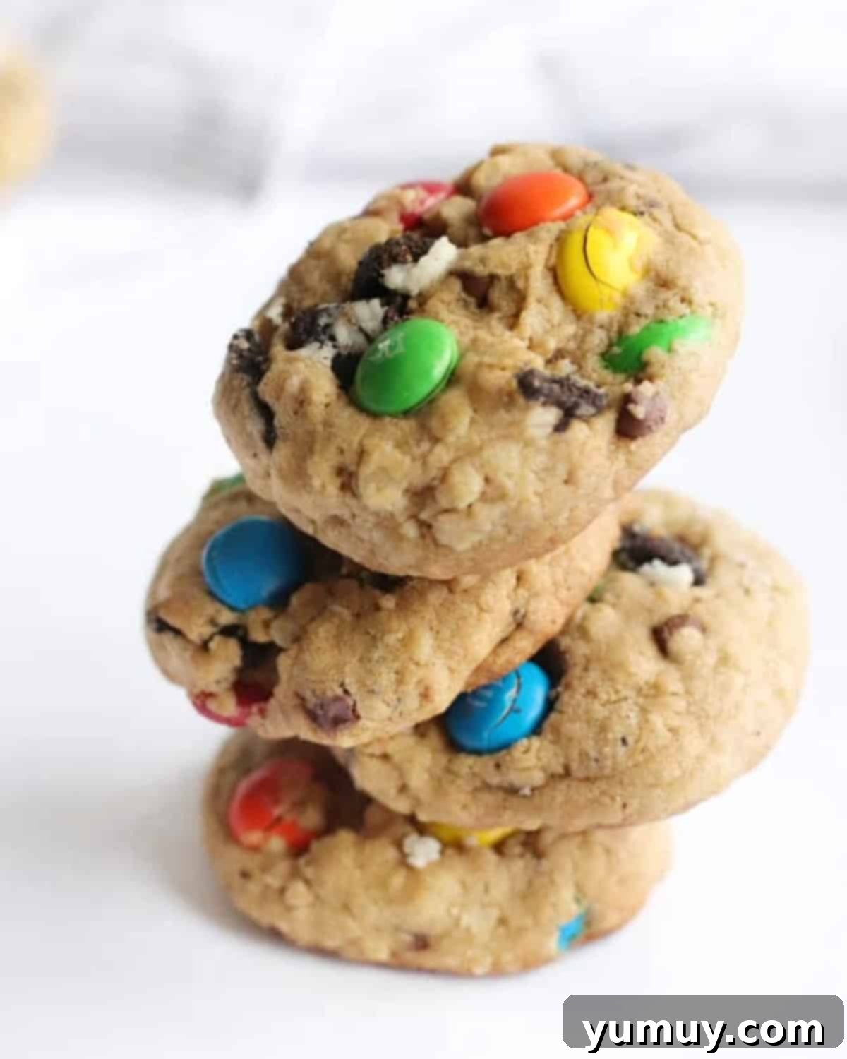 Four perfectly baked Oreo monster cookies stacked, showcasing their generous mix-ins.