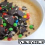 Crumbled Oreos and M&M's piled on top of cookie dough, ready to be folded in.