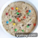 Monster cookie dough resting in a mixing bowl, covered for chilling.