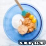 A bowl of creamy peanut butter mixture with a spatula, demonstrating hand-mixing