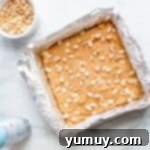 A baking pan filled with golden-brown peanut butter blondies cooling on a wire rack