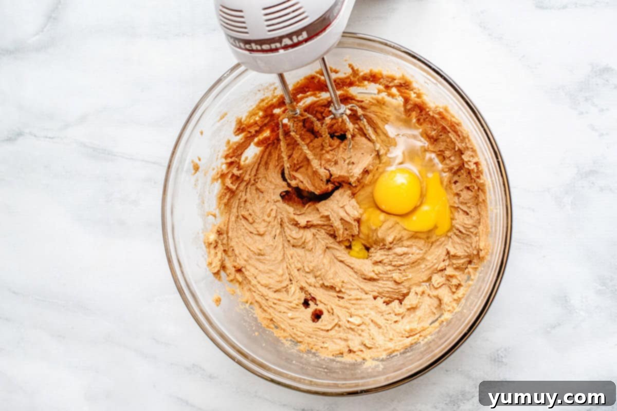 Blending eggs into a bowl of cookie sough.