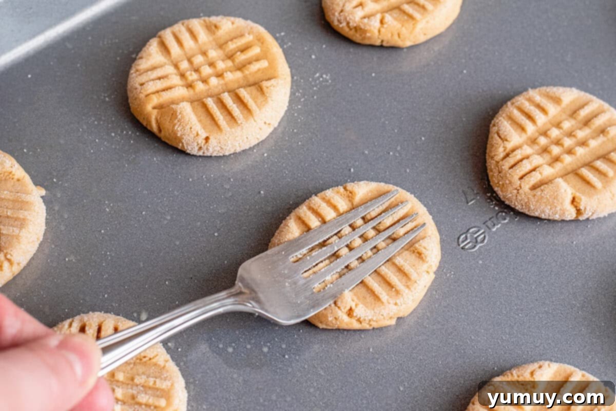 using a fork to press lines into peanut butter cookie dough