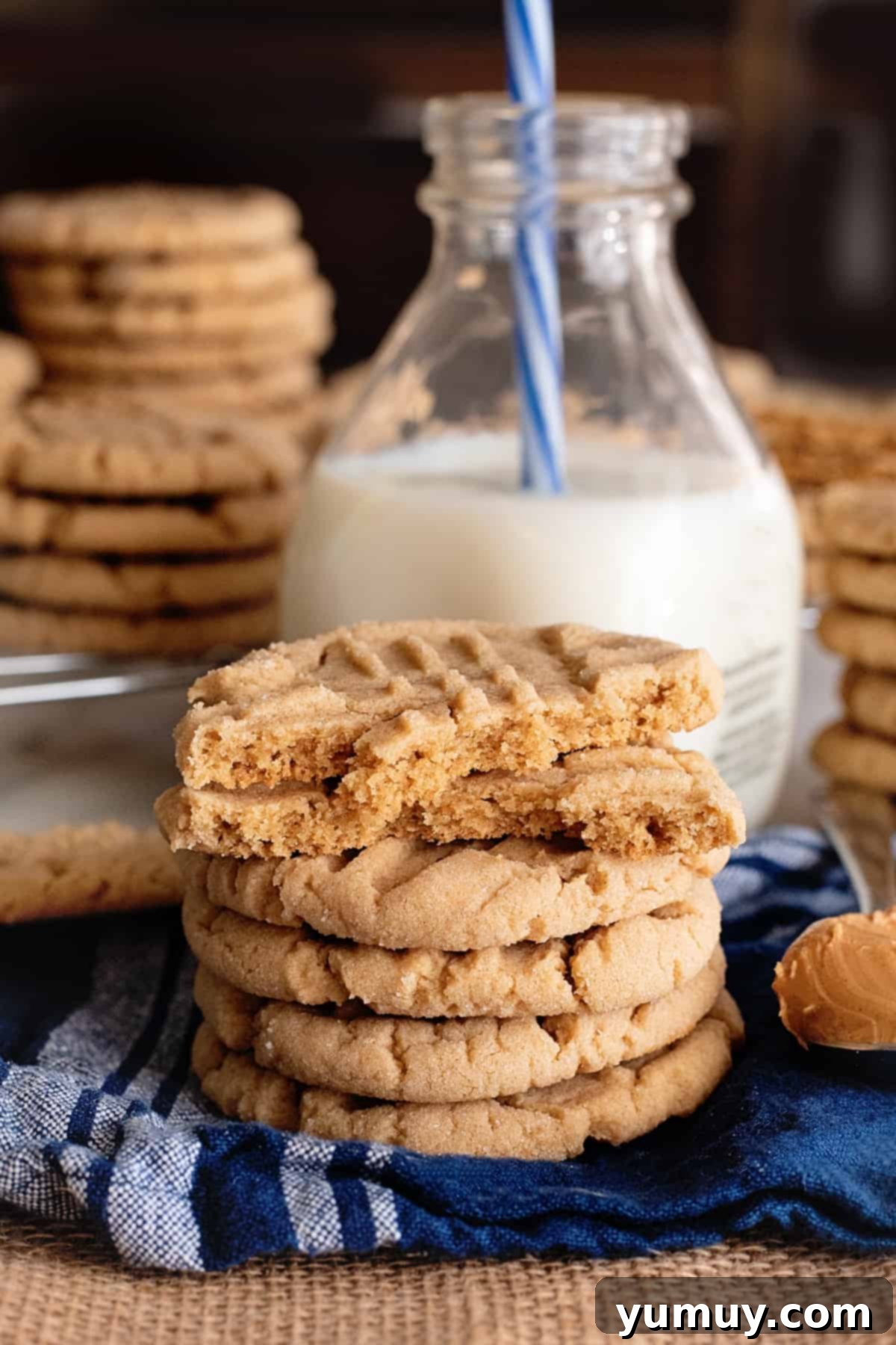 stacks of peanut butter cookies surrounding a jar of milk