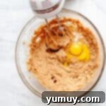 a bowl of brown dough with a blender and egg yolk.