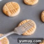 using a fork to press lines into peanut butter cookie dough