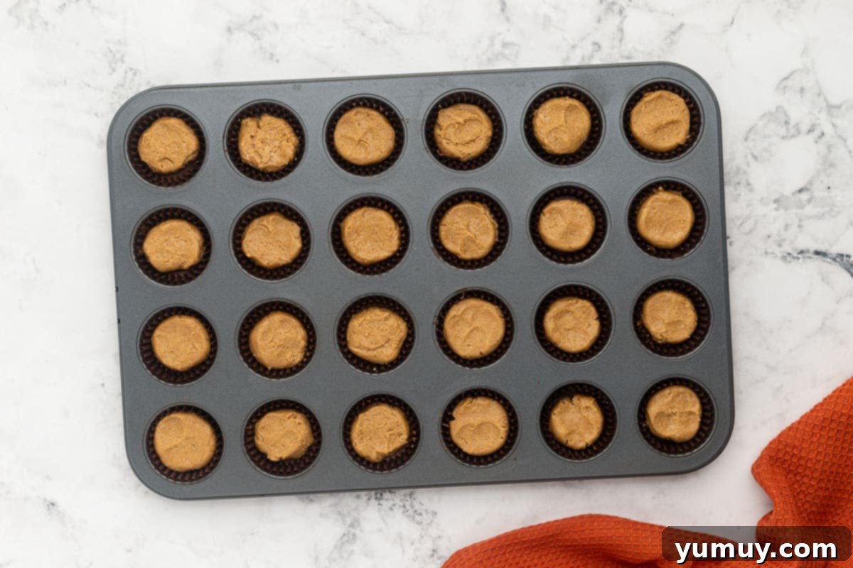 Step 5: Adding a spoonful of peanut butter filling to each chocolate-lined cup.