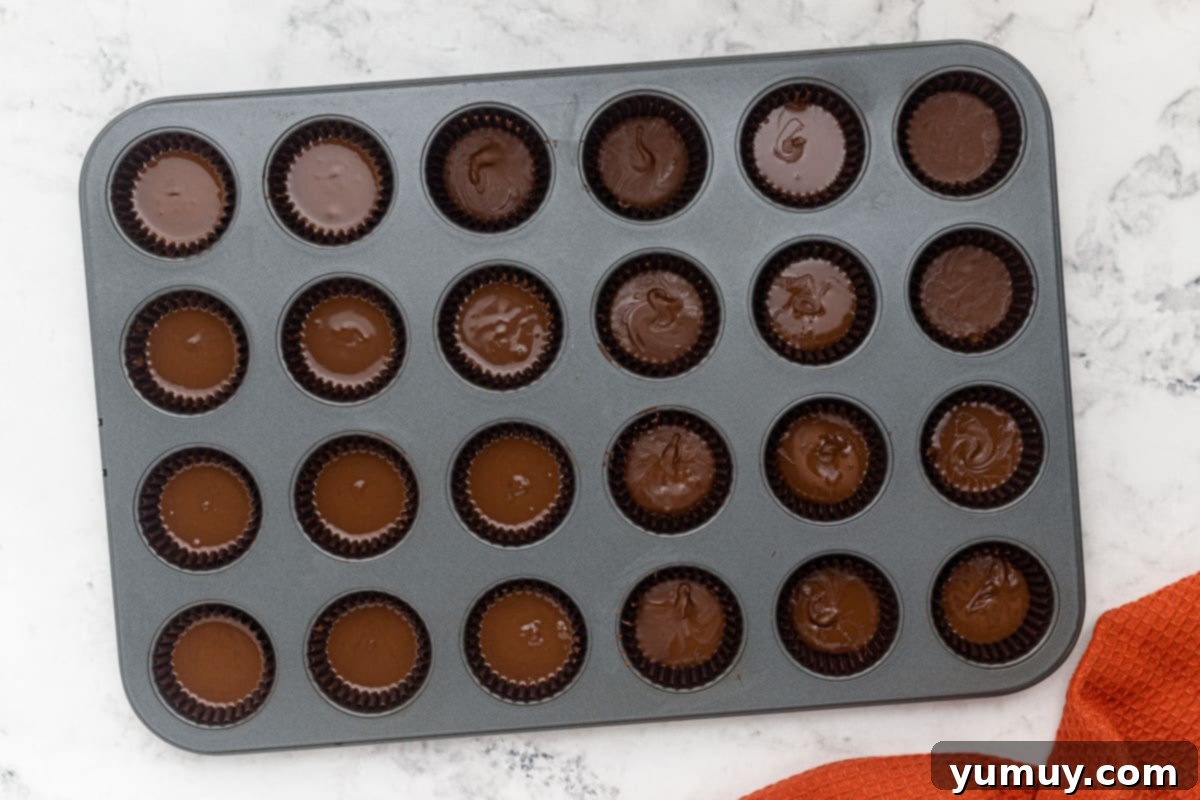 Step 6: Pouring the final layer of melted chocolate over the peanut butter cups.