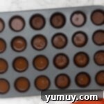 Topping homemade peanut butter cups with a final layer of chocolate.