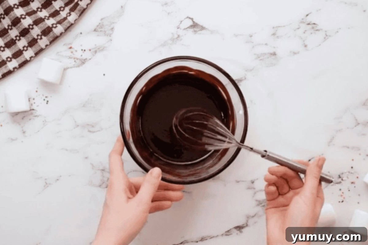 melted chocolate and butter in a glass bowl with a whisk.