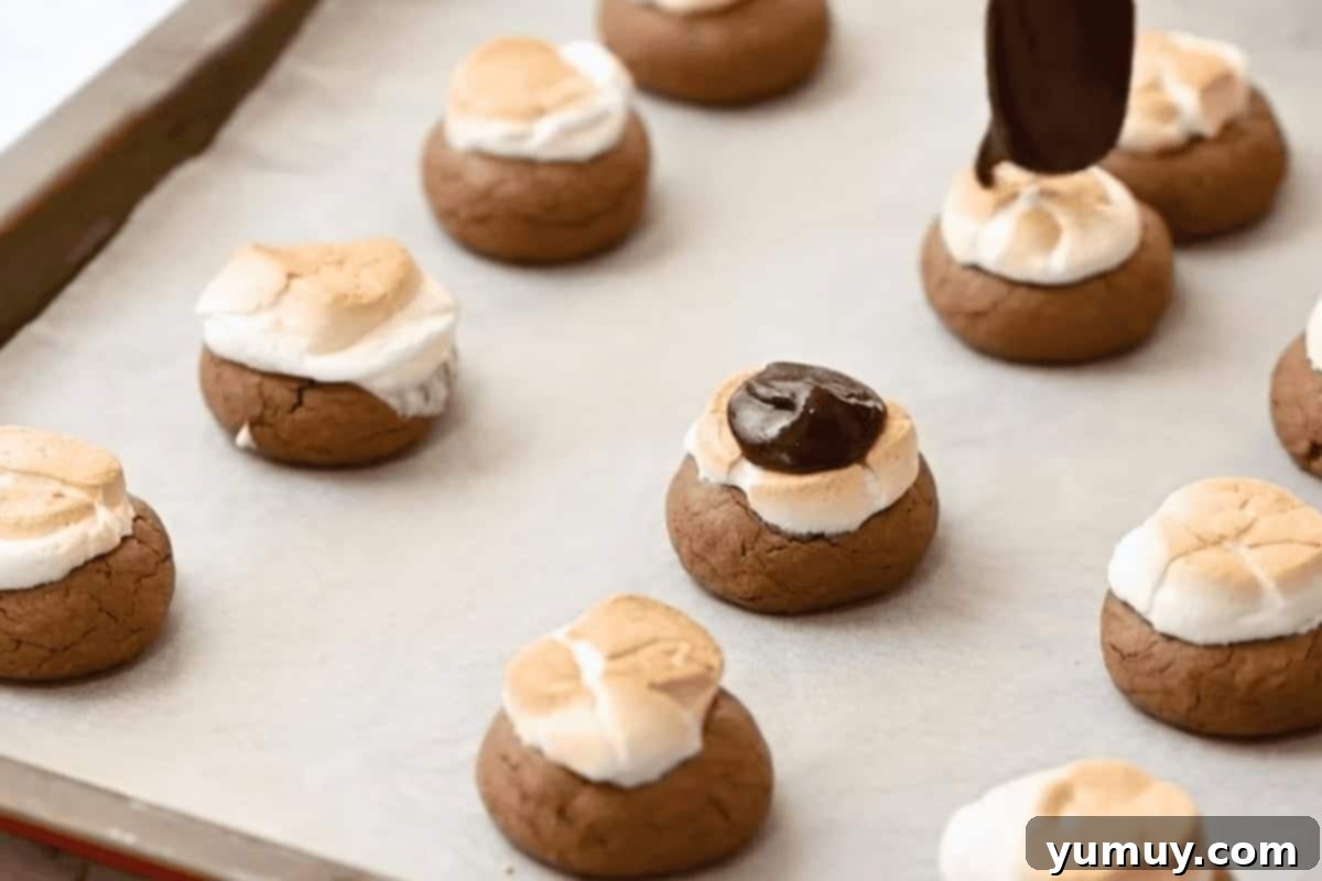 topping hot chocolate cookies with melted chocolate on a baking sheet.