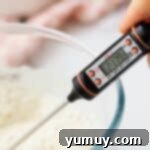 An instant-read food thermometer inserted into a bowl of flour, displaying the temperature to ensure it's properly heat-treated.