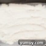Heat-treated flour cooling on a baking tray after being removed from the oven, showing its lightly toasted appearance.