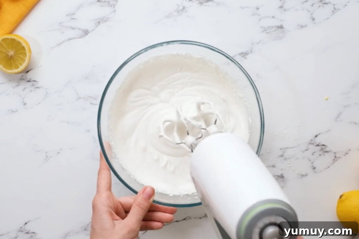 whipping cream in a glass bowl with a hand mixer.